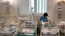 Perawat merawat bayi yang baru lahir dari skema ibu pengganti (surrogate mother) di Hotel Venice, Kiev, Ukraina, 15 Mei 2020. Hingga kini, 100 bayi itu masih menanti orangtua mereka yang berasal dari 12 negara termasuk Inggris, AS, Italia, China, Meksiko, Jerman, dan Prancis. (Sergei SUPINSKY/AFP)