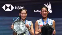 Chiharu Shida (kiri) dan Nami Matsuyama (kanan) di podium selama upacara penyerahan trofi setelah memenangkan final ganda putri di All England 2022 Open Badminton Championship di Utilita Arena di Birmingham, Inggris tengah, pada 20 Maret 2022. (JUSTIN TALLIS / AFP)