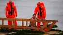 Petugas penyelamat mengamati seorang penganut Ortodoks Rusia yang berendam dalam air es saat perayaan tradisional Epiphany di Kronstadt, luar St. Petersburg, Rusia,  18 Januari 2023. Ribuan pengikut Gereja Ortodoks Rusia terjun ke sungai dan kolam es di seluruh negeri untuk menandai Epiphany, membersihkan diri dengan air yang dianggap suci untuk hari itu. (AP Photo/Dmitri Lovetsky)