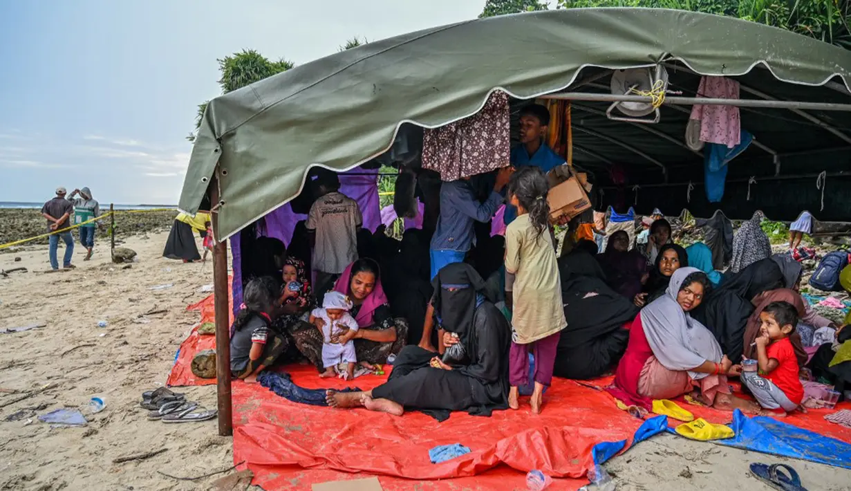 Seratusan pengungsi Rohingya kembali berlabuh Aceh. Hingga Minggu pagi, para pengungsi  ini masih berkumpul di pinggir pantai, setelah turun dari sebuah kapal kayu. (CHAIDEER MAHYUDDIN/AFP)