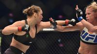 Ronda Rousey, berusaha memukul Holly Holm, pada pertarungan perebutan gelar juara kelas bantam UFC Women di Stadion Etihad, Melbourne, Minggu (15/11/2015). (AFP Photo/Paul Crock)