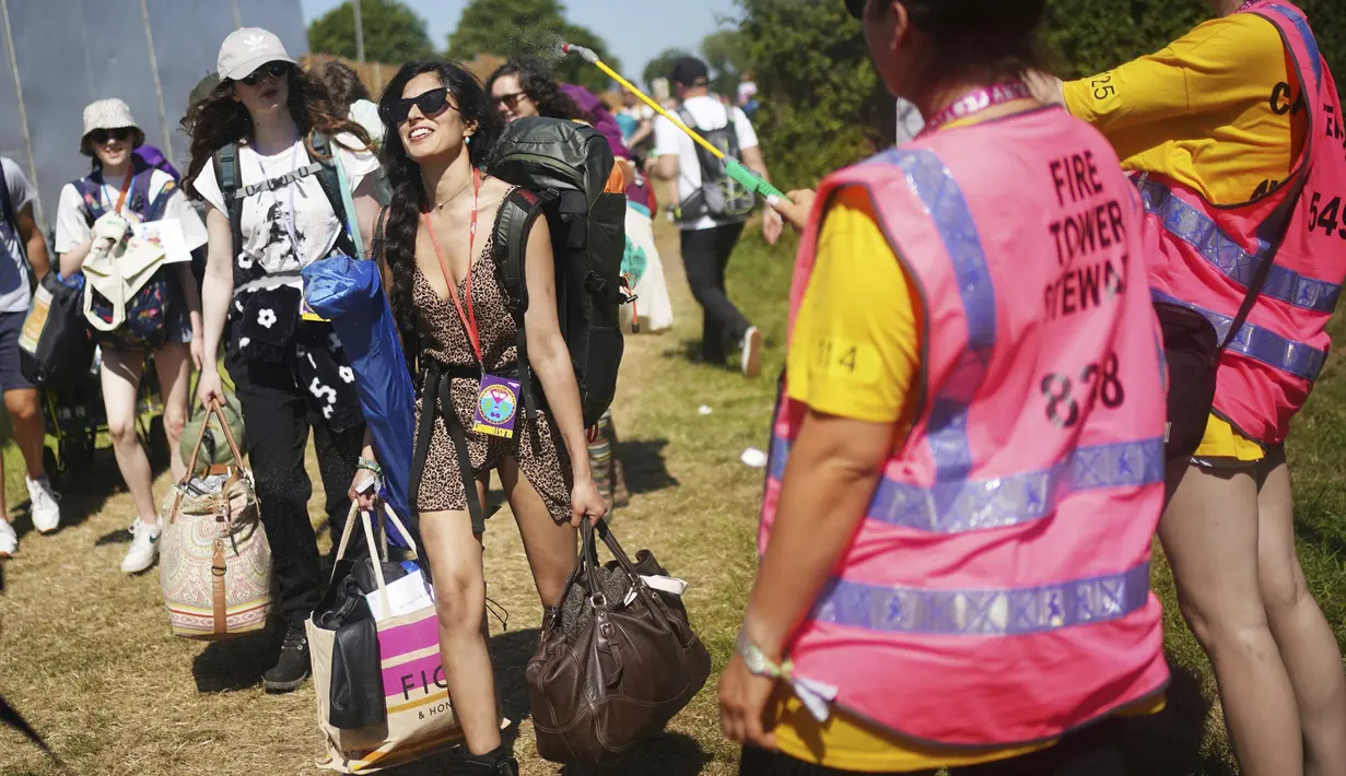 Seorang wanita disemprot air oleh petugas pada hari pertama Festival Glastonbury di Worthy Farm di Somerset, Inggris, Rabu (22/6/2022). Lebih dari 200.000 penggemar musik dan megabintang Paul McCartney, Billie Eilish, dan Kendrick Lamar turun ke pedesaan Inggris minggu ini saat Festival Glastonbury kembali setelah festival jeda tiga tahun. (Yui Mok/PA via AP)