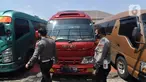 Petugas polisi memeriksa mobil travel gelap yang disita di halaman Polres Metro Kabupaten Bekasi, Jawa Barat, Senin (10/5/2021). Satlantas Polres Metro Bekasi mengamankan 32 travel gelap yang masih beroperasi saat larangan mudik dari tanggal 6-17 Mei 2021. (Liputan6.com/Herman Zakharia)