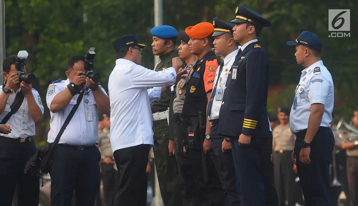 Menhub Budi Karya menyematkan tanda kepada petugas yang akan bertugas selama musim mudik lebaran pada apel di lapangan parkir Stasiun Gambir, Jakarta, Selasa (5/6). Apel diikuti oleh petugas gabungan dari PT KAI, TNI, dan Polri. (Merdeka.com/Imam Buhori)