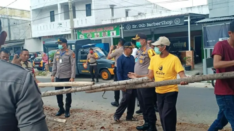 Warga membuka plang kayu yang menutup jalan perumahan setelah diminta Kapolresta Pekanbaru.