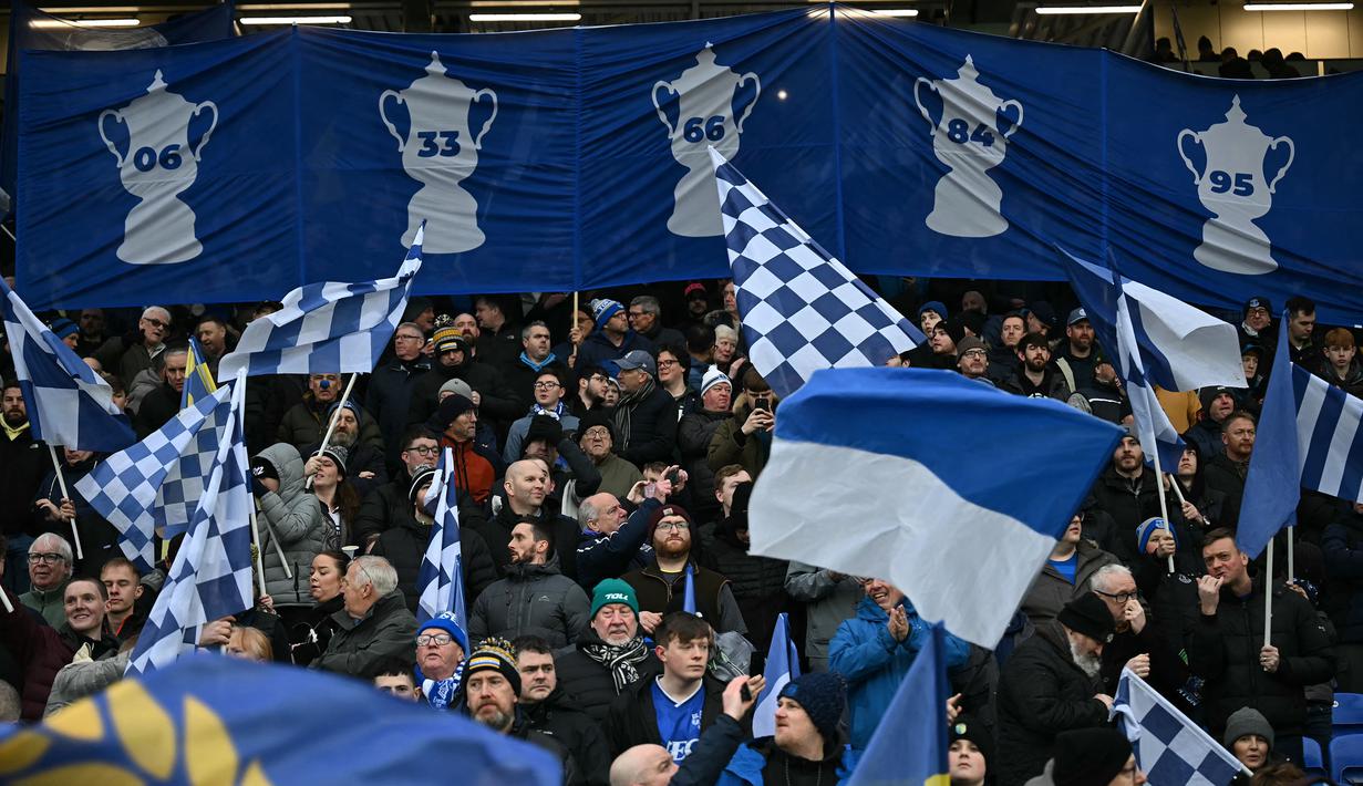 Suporter Everton mengibarkan bendera dan banner dalam laga lanjutan Piala FA 2024/2025 melawan Bournemouth di Goodison Park, Liverpool, Inggris, Minggu (09/02/2025) WIB. (AFP/Paul Ellis)