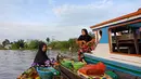 Para pedangan Pasar Terapung Lok Baintan menghampiri perahu kelotok pengunjung dengan sampan atau jukung (Liputan6.com/Pool/Kadek Arini)