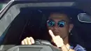 Berada di balik kemudi Lamborghini Urus, Ronaldo yang menggunakan kaca mata tertangkap kamera mengangkat jempolnya saat melewati fans dan para awak media. (Foto: AFP/Paul Ellis)
