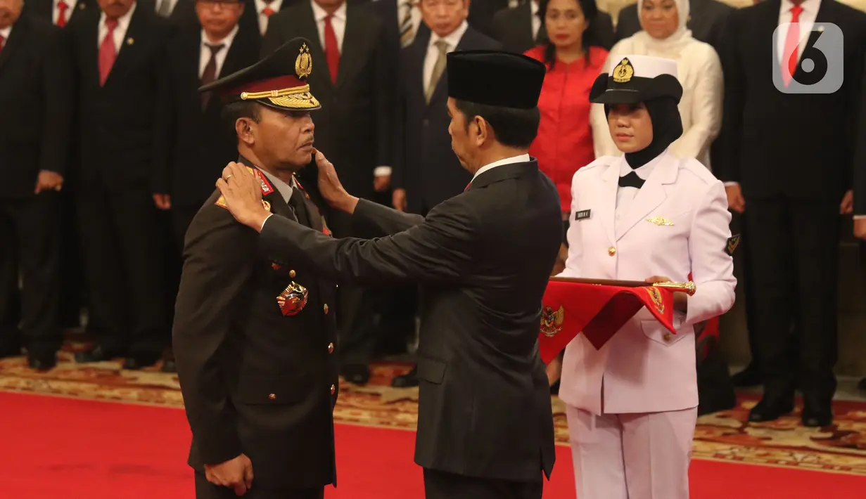 Presiden Joko Widodo atau Jokowi (kanan) memasangkan pangkat jabatan kepada Kapolri Idham Azis saat upacara pelantikan di Istana Negara, Jakarta, Jumat (1/11/2019). Idham Azis dilantik menjadi Kapolri menggantikan Tito Karnavian yang diangkat menjadi Mendagri. (Liputan6.com/Angga Yuniar)