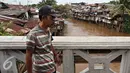 Warga berjalan dijembatan bantaran Kali Ciliwung, Jakarta, Rabu (20/1). Apabila rusun yang disediakan telah siap ditempati Pemprov DKI Jakarta akan melakukan penggusuran pemukiman kumuh sebanyak mungkin. (Liputan6.com/Immanuel Antonius)