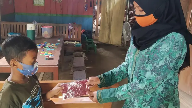 Puji Lestari saat menyambangi peserta didik dari rumah ke rumah. Selain memberikan pembelajaran sekolah, peserta didiknya juga dilatih dan diberi pengetahuan tentang 3 M.(Liputan6.com/Ahmad Adirin)