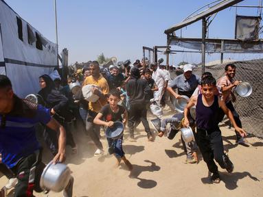 Warga Palestina berlarian untuk mengantre di sebuah dapur umum yang ada di daerah Mawasi, Khan Yunis, Jalur Gaza selatan pada 22 Juli 2025. (Foto oleh AFP)