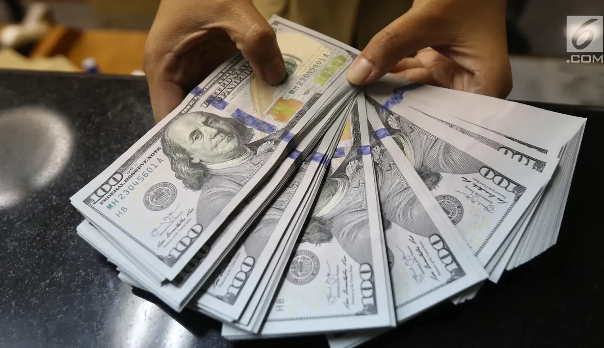 Pekerja menunjukan Dolar AS di jasa penukaran uang asing di Jakarta, Rabu (19/6/2019). Nilai tukar rupiah terhadap Dolar AS sore ini Rabu (19/6) ditutup menguat sebesar Rp 14.269 per dolar AS atau menguat 56,0 poin (0,39 persen) dari penutupan sebelumnya. (Liputan6.com/Angga Yuniar)