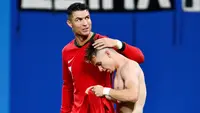 Pemain Portugal, Cristiano Ronaldo, memberikan selamat kepada Francisco Conceicao yang telah mencetak gol ke gawang Republik Ceko dalam duel matchday 1 Grup F Euro 2024, Rabu (19/6/2024). Portugal menang dengan skor 2-1. (AFP/Christophe Simon)