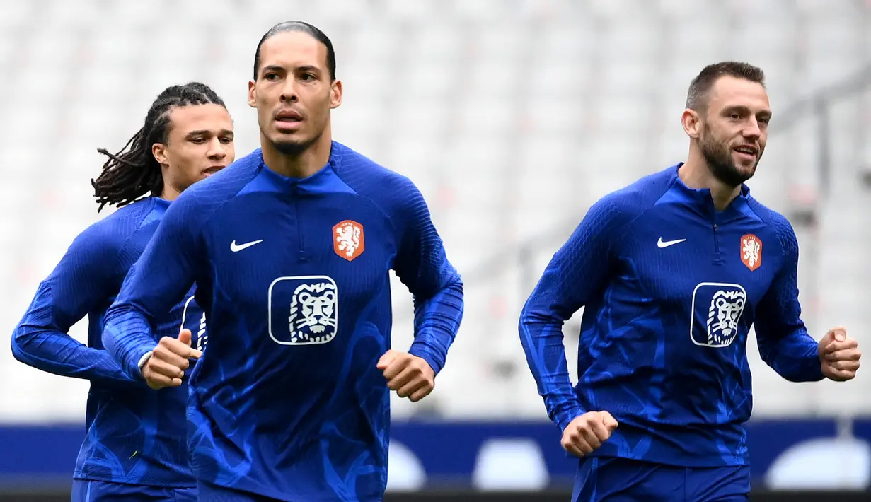 Bek Belanda Nathan Ake (kiri) dan bek Belanda Virgil Van Dijk (tengah) melakukan pemanasan dalam sesi latihan di Stade de France di Saint-Denis, utara Paris pada 23 Maret 2023. (AFP/Franck Fife)