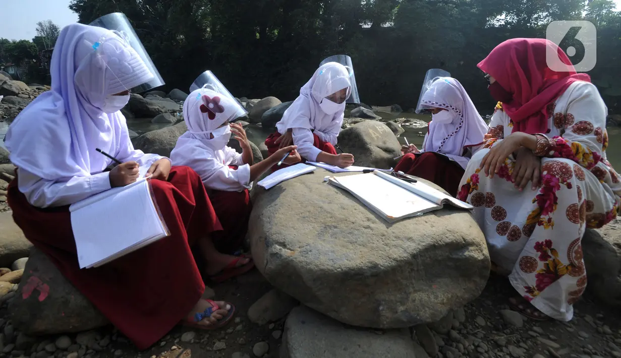 Siswa kelas 3 SDN II Roda Kota Bogor dan pendamping yang memiliki smartphone belajar kelompok secara daring di pinggir sungai Ciliwung, Kampung Kebon Jukut RT 01/10, Babakan Pasar, Kamis (6/8/2020). Kegiatan itu untuk mendapatkan jaringan internet yang baik di masa pandemi. (merdeka.com/Arie Basuki)