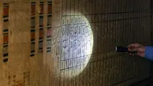 Seorang arkeolog memegang lampu senter di dinding yang ditutupi ukiran hieroglif di makam Beti, salah satu dari lima makam Firaun kuno di situs arkeologi Saqqara, Kairo, Mesir (19/3/2022). Menurut Waziri, lima makam yang semuanya dalam kondisi baik itu milik petinggi kerajaan. (AFP/Khaled Desouki)