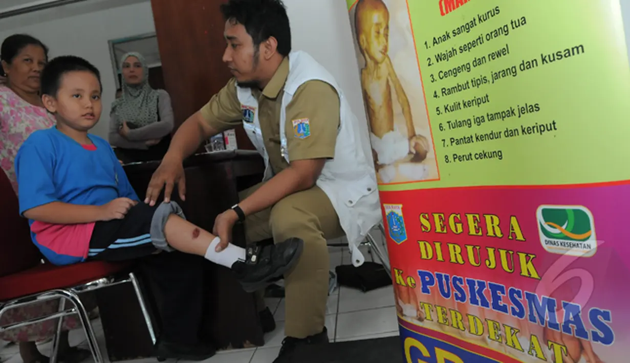 Seorang petugas sedang melayani seorang bocah yang kakinya sakit di Puskesmas Rusunawa Tambora, Jakarta, Selasa (24/2/2015). (Liputan6.com/Herman Zakharia)