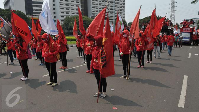 Sejumlah wanita membawa bendera saat aksi Hari Buruh di Jakarta, Senin (1/5). Dalam aksinya para buruh meminta sistem kerja kontrak dan upah rendah dihapus. (Liputan6.com/Helmi Afandi)