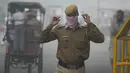 Polisi India menutup wajahnya dengan saputangan saat melewati jalan di New Delhi yang diselimuti kabut asap akibat polusi udara, Rabu (8/11). Organisasi Kesehatan Dunia menempatkan New Delhi sebagai kota paling berpolusi di dunia. (SAJJAD HUSSAIN/AFP)