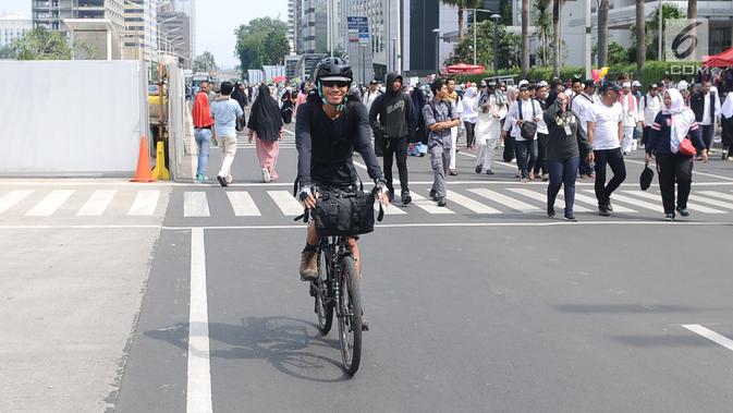 Seorang warga bersepeda di antara peserta Reuni 212 saat Car Free Day (CFD) di kawasan Jakarta, Minggu (2/12). Warga tetap memadati area Car Free Day  dari Bundaran HI-Sudirman meskipun ada aksi Reuni 212. (Liputan6.com/Angga Yuniar)