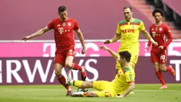 Striker Bayern Munchen, Robert Lewandowski, berusaha melewati pemain FC Koln, Jorge Meré, pada laga Bundesliga di Stadion Allianz, Minggu (27/2/2021). Bayern menang dengan skor 5-1. (AP/Andreas Schaad)