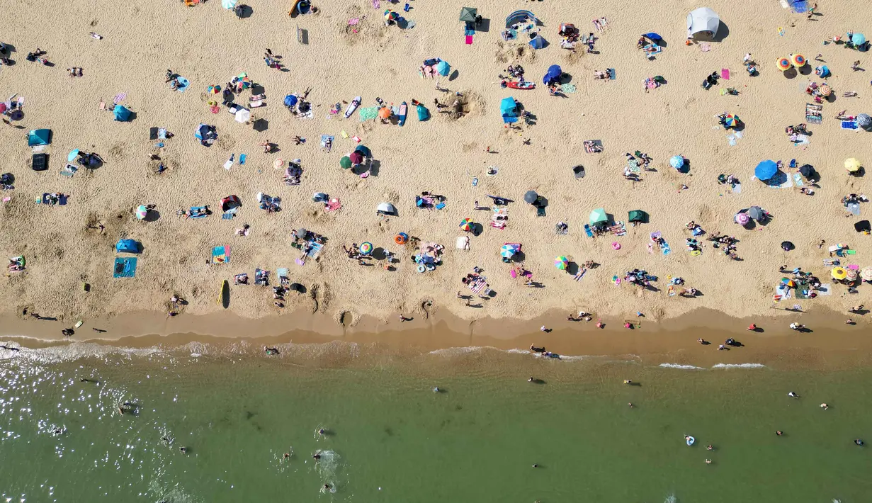 Foto udara menunjukkan orang-orang bermain dan bersantai di bawah sinar matahari di Pantai Bournemouth, Selatan Inggris pada Selasa 26 Mei 2026, saat kondisi gelombang panas menyebar ke sebagian wilayah tenggara Inggris dan London. (JUSTIN TALLIS/AFP)