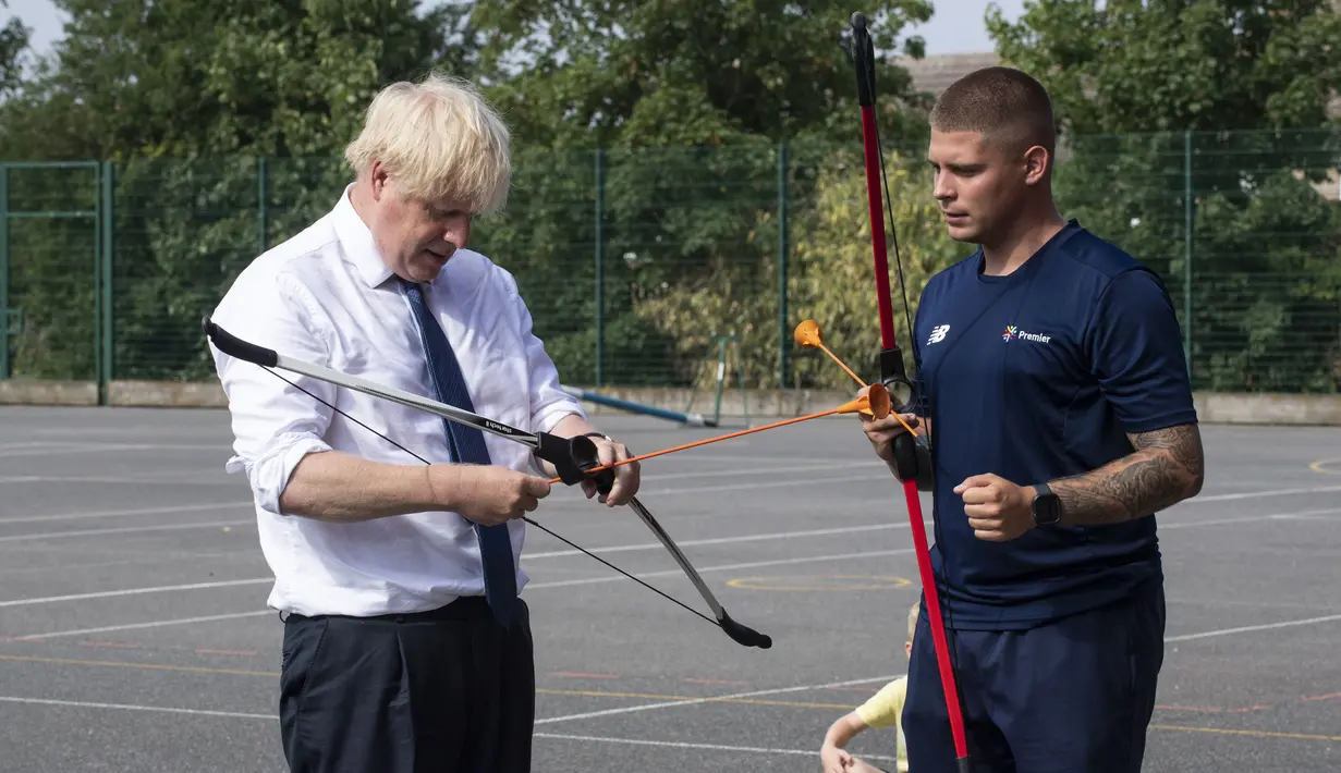 PM Inggris Boris Johnson bermain panahan saat mengunjungi Premier Education Summer Camp di Sacred Heart of Mary Girl's School, Upminster, Inggris, Senin (10/8/2020). Kunjungan Boris untuk melihat persiapan jelang pembukaan kembali sekolah pada September mendatang. (Lucy Young/Pool via AP)