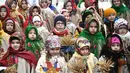 Mengenakan pakaian tradisional, warga Ukraina bernyanyi bersama sambil membawa 'Didukh'. 'Didukh' merupakan simbol Natal tradisional Ukraina. Tampak dalam foto, anak-anak yang mengenakan pakaian tradisional dan membawa hiasan tradisional Natal Ukraina 'Didukh' dalam prosesi Malam Natal di Lviv pada 24 Desember 2025. (YURIY DYACHYSHYN/AFP)