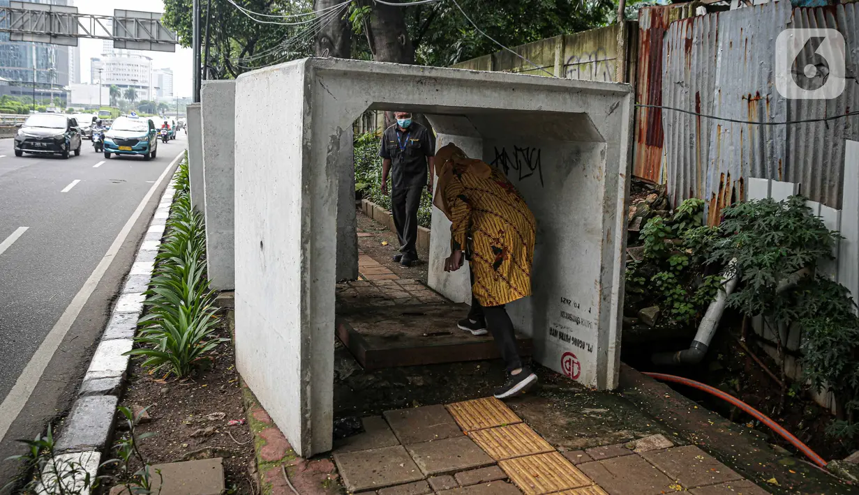 Pejalan kaki melintas di antara beton saluaran air yang berada di jalur pedestrian kawasan Gatot Subroto, Jakarta, Selasa (21/12/2021). Selain mengganggu kenyamanan, keberadaan beton saluran air tersebut juga dapat membahayakan pejalan kaki yang melintas. (Liputan6.com/Faizal Fanani)
