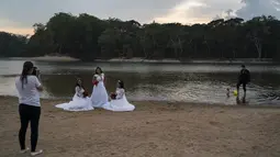 Eliene Pereira Francisco (tengah) berpose untuk foto untuk album pernikahan dengan putrinya Jaiane Pereira Marsal (kiri) dan Gislaine Pereira de Araujo dengan latar belakang hutan hujan Amazon di pantai sungai Jamanxim di Novo Progresso, Brasil (2/9/2019). (AP Photo/Leo Correa)