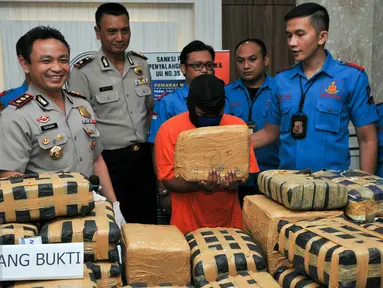 Tersangka MS (tengah) menunjukkan ganja miliknya seberat 219 kg, Jakarta, Kamis (3/12/2015). Tersangka MS dijerat pasal berlapis dengan ancaman hukuman mati. . (Liputan6.com/Yoppy Renato)