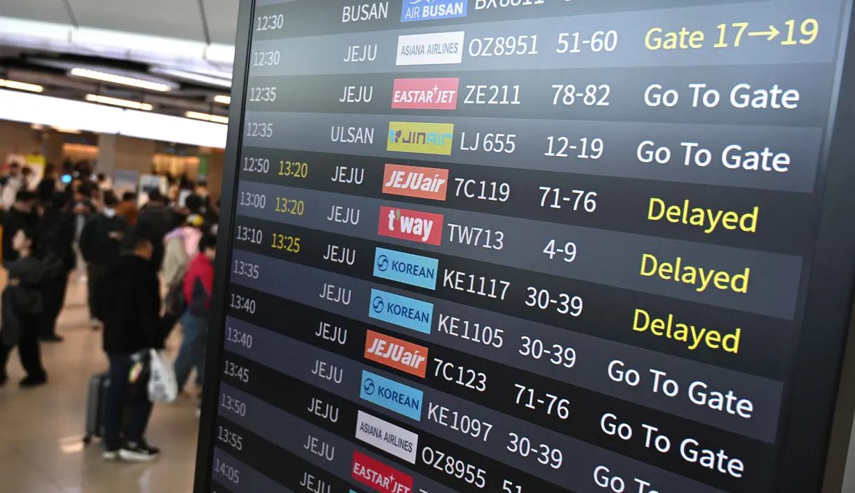 Penumpang berjalan melewati papan informasi yang menampilkan penerbangan tertunda di Bandara Gimpo, Seoul, pada Kamis 13 November 2025, pada hari ujian masuk perguruan tinggi tahunan yang dikenal secara lokal sebagai Suneung. (Jung Yeon-je/AFP)