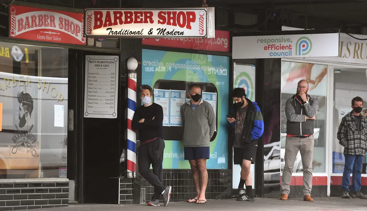 Para pria antre untuk memotong rambut di luar barber shop di Melbourne, Australia, Senin (19/10/2020). Warga Kota Melbourne, pada Senin (19/10), akhirnya bisa bernafas lega saat sejumlah pembatasan dilonggarkan setelah lockdown tahap keempat yang ketat selama sekitar 100 hari. (William WEST/AFP)