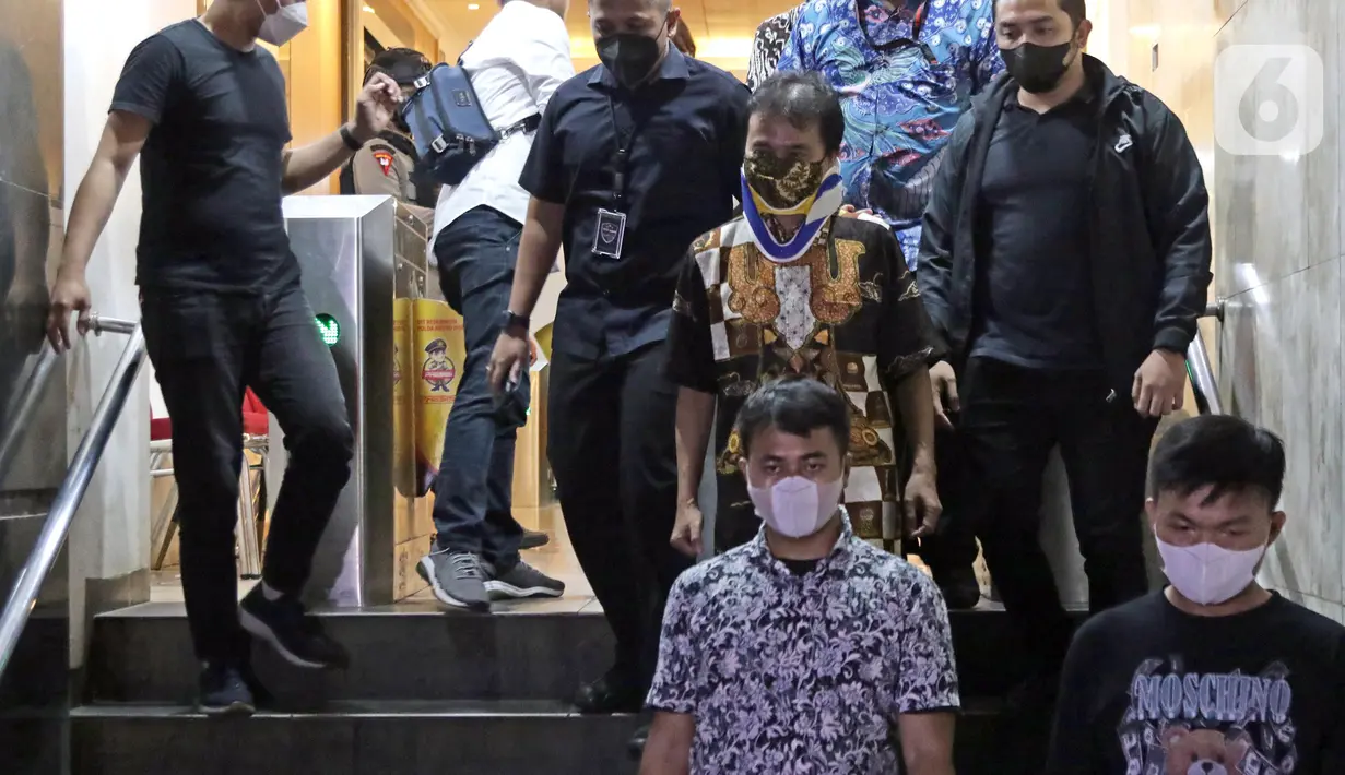 Petugas mengawal mantan Menteri Pemuda dan Olahraga Roy Suryo (tengah) saat menuju rutan usai menjalani pemeriksaan di Direktorat Reskrimum Polda Metro Jaya, Jakarta, Jumat (5/8/2022). Roy Suryo ditahan sebagai tersangka kasus dugaan penistaan agama terkait unggahan meme stupa Candi Borobudur berwajah mirip Presiden Joko Widodo. (Liputan6.com/Helmi Fithriansyah)