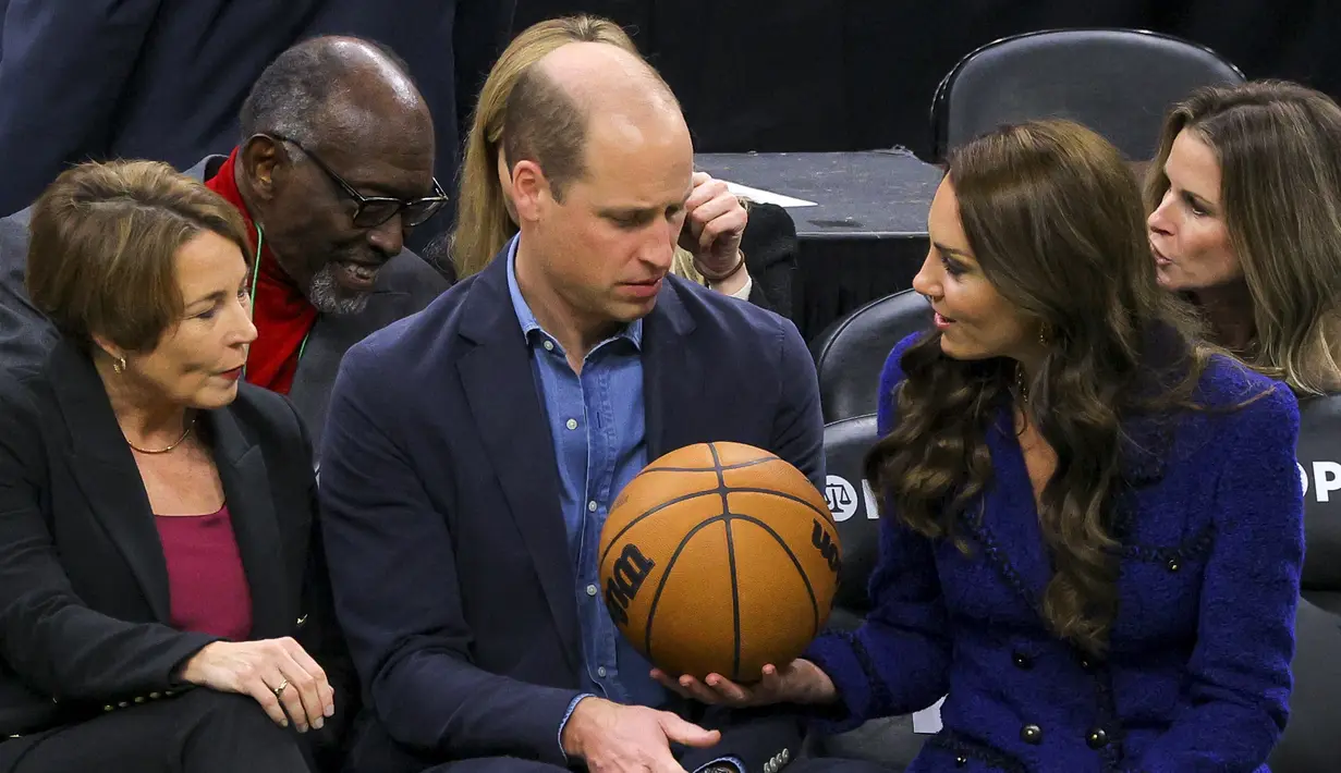 Kate Middleton, Putri Wales memberikan bola basket kepada Pangeran Inggris William disaksikan Gubernur terpilih Massachusetts Maura Healey (kiri) selama pertandingan NBA antara Boston Celtics dan Miami Heat di TD Garden di pusat kota Boston, pada 30 November 2022. (Photo by Brian Snyder/Pool/AFP)