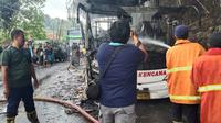 Petugas Pemadam Kebakaran sedang melakukan pendinginan bus AKAP yang terbakar.