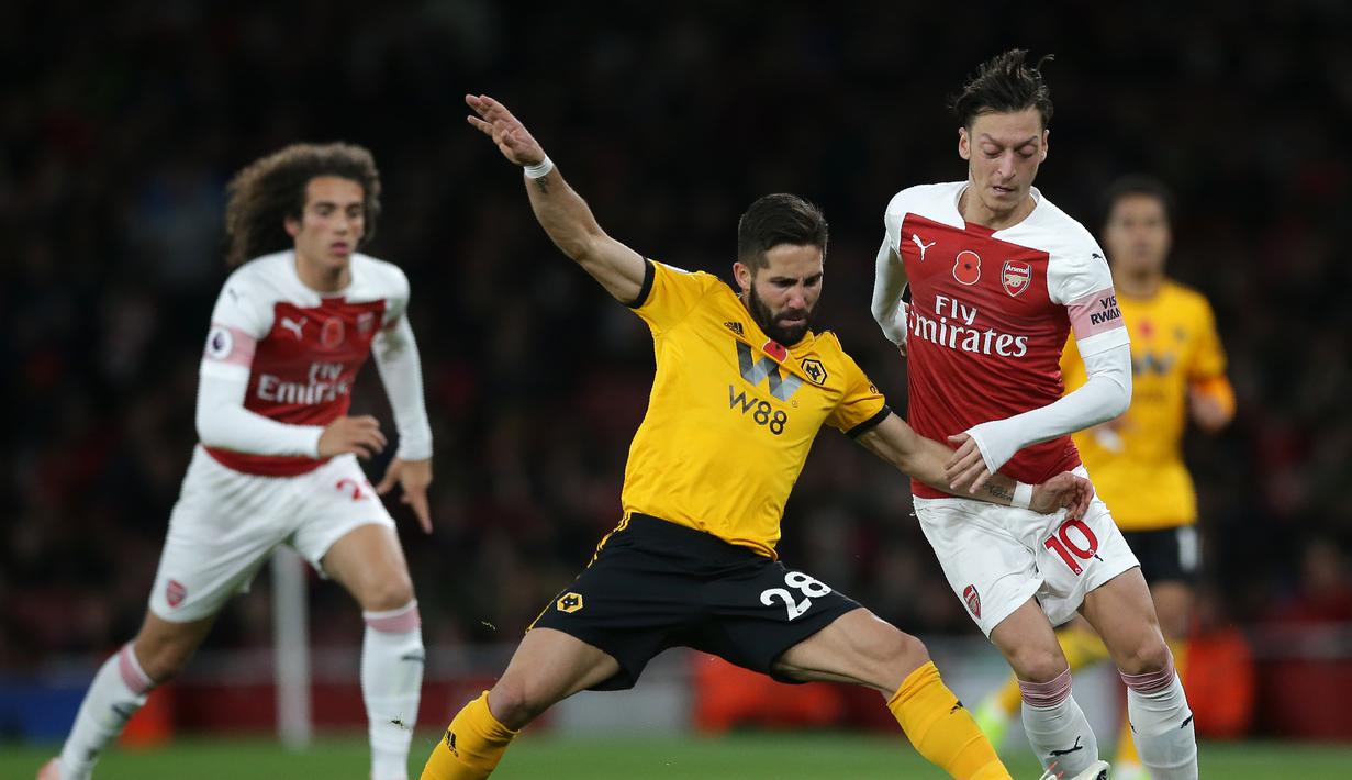 Aksi Mesut Ozil saat berduel dengan pemain Wolverhampton pada laga lanjutan Premier League, yang berlangsung Minggu (11/11) di stadion Emirates. Arsenal ditahan imbang Wolverhampton 1-1. (AFP/Daniel Olivas)