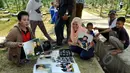 Seorang pedagang menunjukkan poster dagangannya yang bergambar Olga Syahputra di TPU Malaka, Jakarta, Selasa (31/3/2015). Empat hari pascakepergian komedian Olga, antusiasme masyarakat berkunjung ke makam masih tinggi. (Liputan6.com/Panji Diksana)