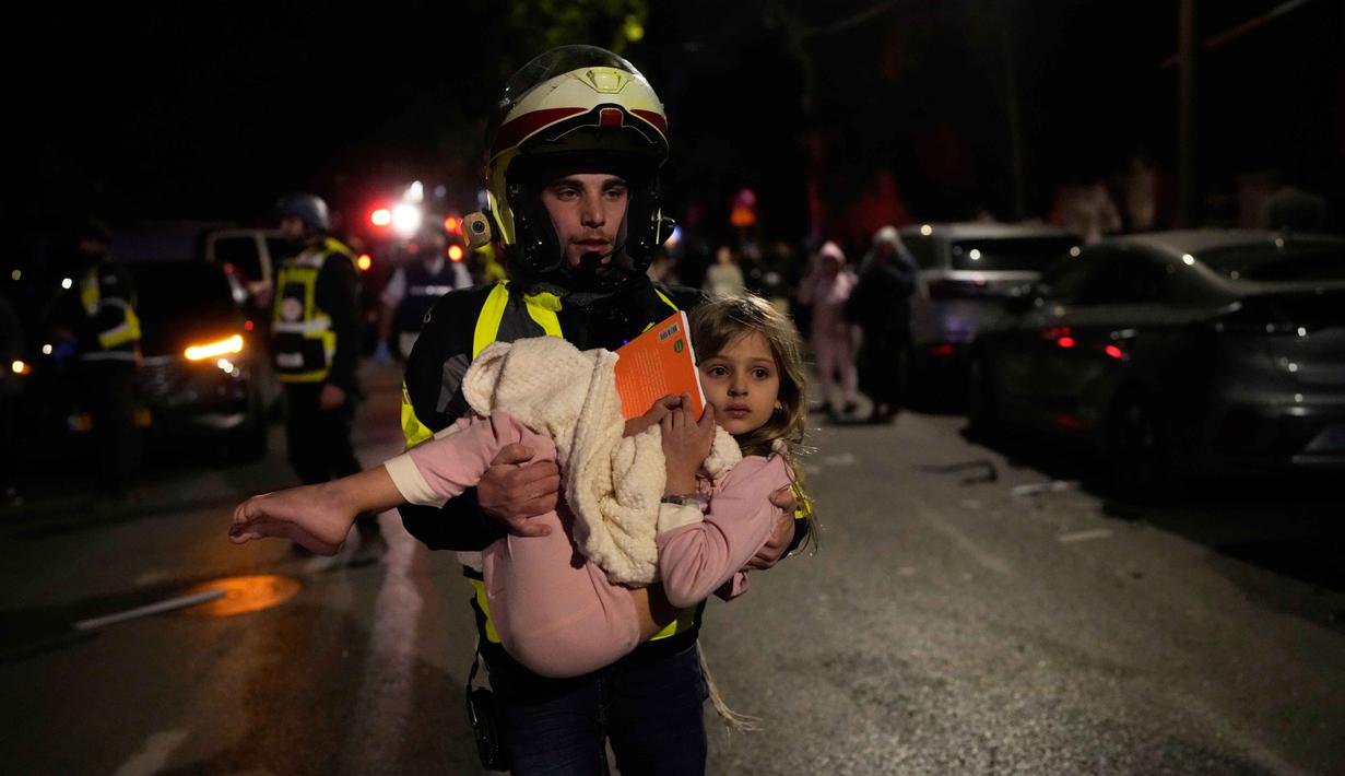 Sebelumnya, Kementerian Pertahanan Israel mengumumkan bahwa pasukan militernya telah melancarkan serangan pendahuluan terhadap Iran. Tampak dalam foto, seorang petugas penyelamat Israel menggendong seorang anak setelah serangan rudal dari Iran menghantam Tel Aviv, Israel, Sabtu 28 Februari 2026. (AP Photo/Ohad Zwigenberg)