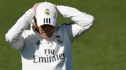 Pelatih Real Madrid Zinedine Zidane merapikan topinya saat menghadiri sesi pelatihan di fasilitas pelatihan Valdebebas di Madrid (15/3). Zidane kembali melatih Real Madrid menggantikan Santiago Solari. (AFP Photo/Gabriel Bouys)