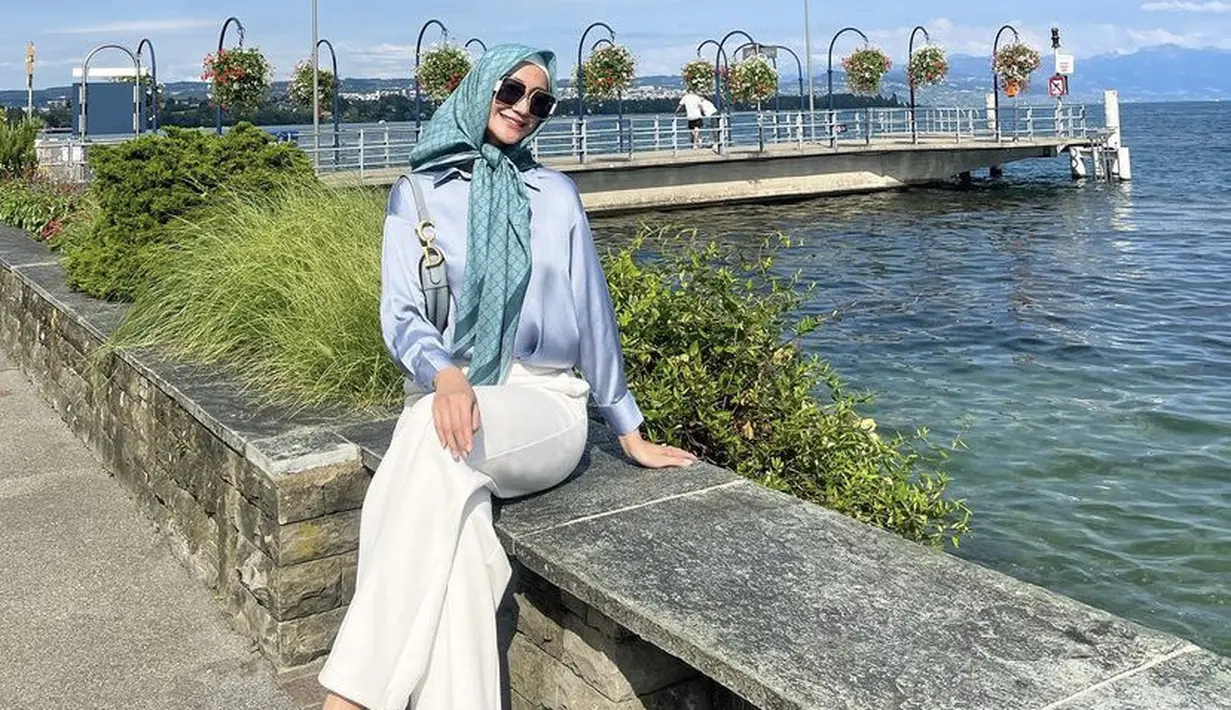 Ayu juga tampil dengan kerudung segi empat warna hijau bermotif, dipadukan kemeja lengan panjang biru dan celana putihnya.  [Instagram/@ayumaulida97]