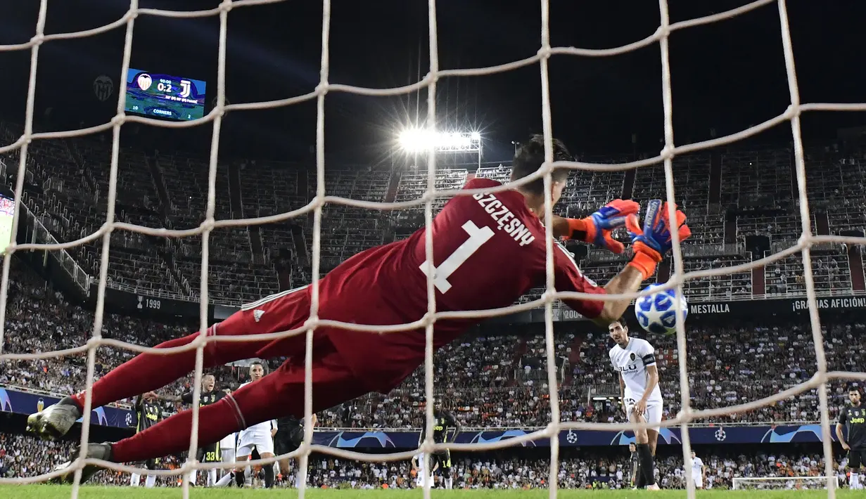Kiper Juventus, Wojciech Szczesny, berusaha menghalau bola saat melawan Valencia pada laga Liga Champions di Stadion Mestalla, Valencia, Rabu (19/9/2018). Juventus menang 2-0 atas Valencia. (AFP/Javier Soriano)