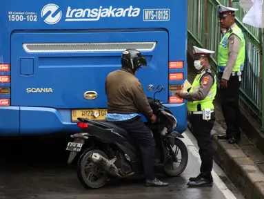 Petugas kepolisian lalu lintas merazia pengendara sepeda motor yang melintasi jalur bus Transjakarta di Jalan Sultan Agung, Manggarai, Jakarta, Kamis (6/2/2020). Meski melanggar, sebagian pengguna jalan secara sengaja masuk dan menggunakan jalur khusus bus tersebut. (Liputan6.com/Helmi Fithriansyah)