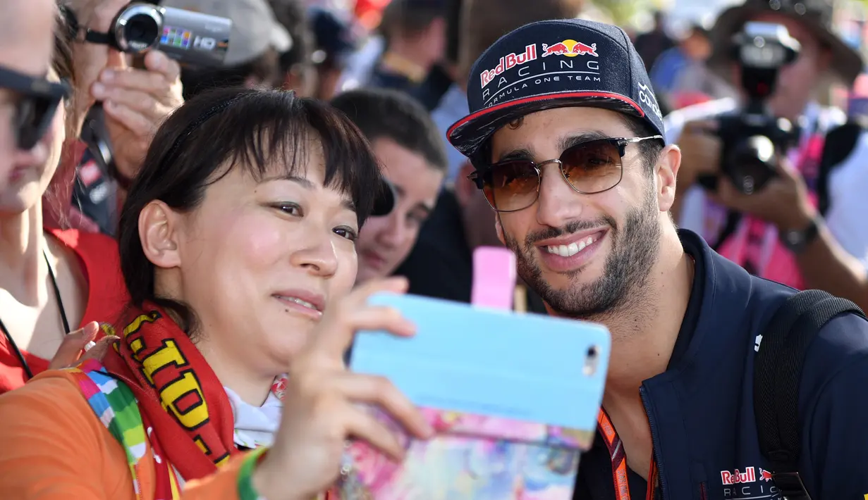 Pembalap Red Bull, Daniel Ricciardo melakukan selfie dengan seorang penggemar menjelang sesi latihan bebas pertama di Grand Prix Australia, Melbourne, Jumat (24/3). (AFP Photo/WILLIAM WEST)