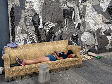 Seorang wanita tidur di sofa yang dibuang di trotoar samping mural lukisan "Guernica" karya Pablo Picasso di lingkungan Padre Carlos Mugica, Buenos Aires, Argentina, Kamis (14/12/2023). Pemerintah Argentina memotong subsidi transportasi dan energi serta mendevaluasi peso sebesar 50 persen sebagai bagian dari tindakan mengejutkan yang menurut Presiden Javier Milei diperlukan untuk menghadapi keadaan darurat ekonomi. (AP Photo/Rodrigo Abd)