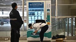Seorang pria menggunakan mesin penjual otomatis (vending machine) yang menyediakan alat test kit COVID-19 di stasiun kereta bawah tanah MTR di Hong Kong, Senin (7/12/2020). Hong Kong menyediakan mesin penjual alat uji COVID-19 di 10 stasiun kereta bawah tanah. (Anthony WALLACE / AFP)