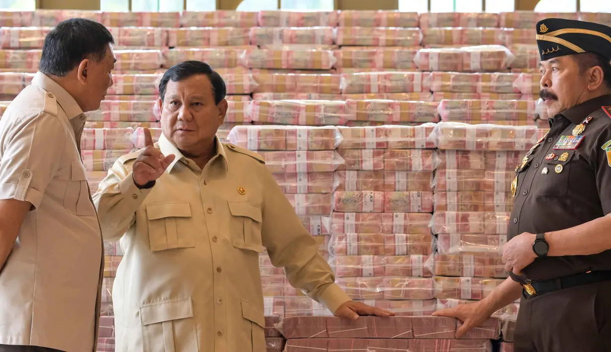Presiden Prabowo Subianto (tengah) berbicara dengan Jaksa Agung Sanitiar Burhanuddin (kanan) dan Menteri Pertahanan Indonesia Sjafrie Sjamsoeddin di samping tumpukan uang kertas rupiah Indonesia senilai 800 juta USD di gedung Kejaksaan Agung Republik Indonesia, Jakarta, Senin 20 Oktober 2025. (BAY ISMOYO/AFP)
