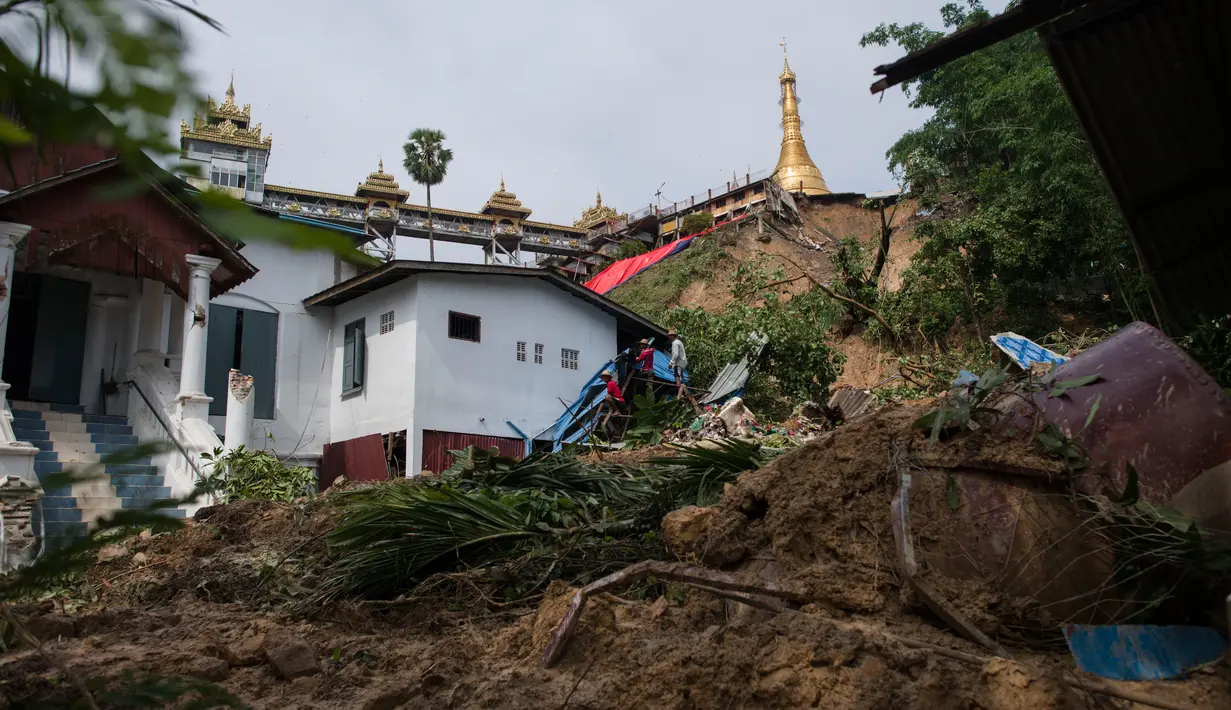 Pekerja membersihkan puing-puing akibat tanah longsor yang merusak pagodha di puncak bukit Kyeik Than Lan, Myanmar (18/6). Hujan deras memicu tanah longsor yang merusak pagoda. (AFP PHOTO / Ye Aung Thu)