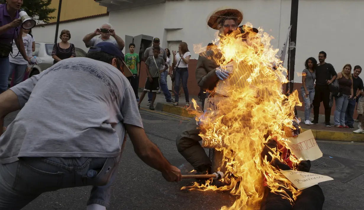 Patung bergambar Presiden Venezuela Nicolas Maduro dibakar oleh warga di Caracas , Venezuela, (27/3). Proses ini juga masuk dalam tradisi " Pembakaran Yudas " tetapi bedanya patung tersebut ditempel gambar Nicolas Maduro. (REUTERS / Marco Bello)